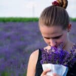 a woman smelling flowers in field