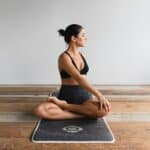 woman sitting on yoga mat in studio